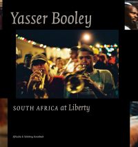 Black book cover of Yasser Booley, South Africa at Liberty, featuring two men playing trumpets, with brass band behind. Published by Stichting.