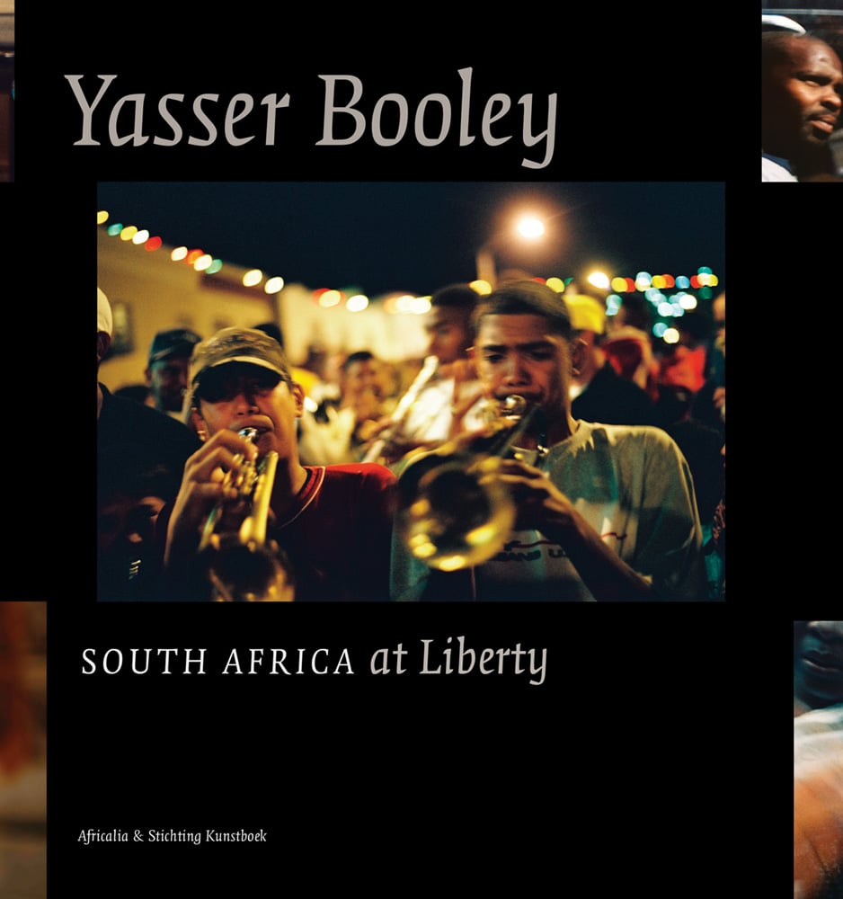 Black book cover of Yasser Booley, South Africa at Liberty, featuring two men playing trumpets, with brass band behind. Published by Stichting.