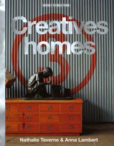 Colour photograph of a corrugated backdrop with the number 3 spray painted inside a circle in orange with seated bronze figure of a boy on top of a chest of drawers with Creative homes in mottled grey and white