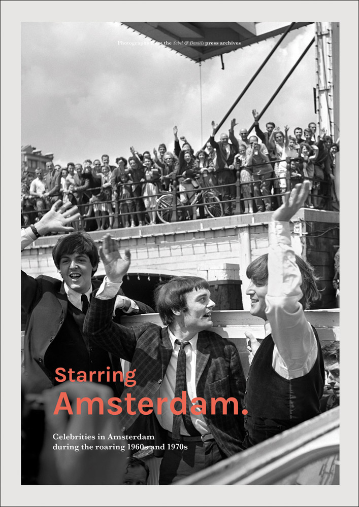 Black and white photograph of John Lennon and Paul McCartney either side of another man waving to crowds of fans standing on a bridge with Starring Amsterdam in red