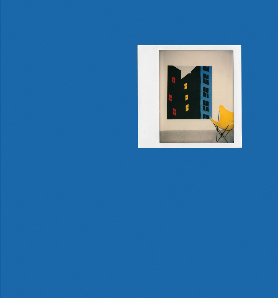 Polaroid shot of painting of blacked out high rise building on blue cover.