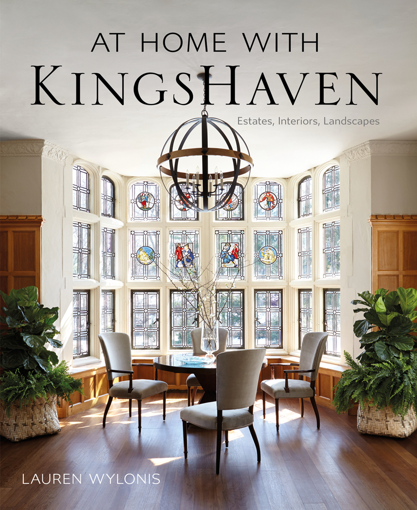 Book cover of At Home with KingsHaven: Estates, Interiors, Landscapes, featuring a light interior space with wood floor, and table and chairs in front of large stained glass window. Published by Images Publishing.