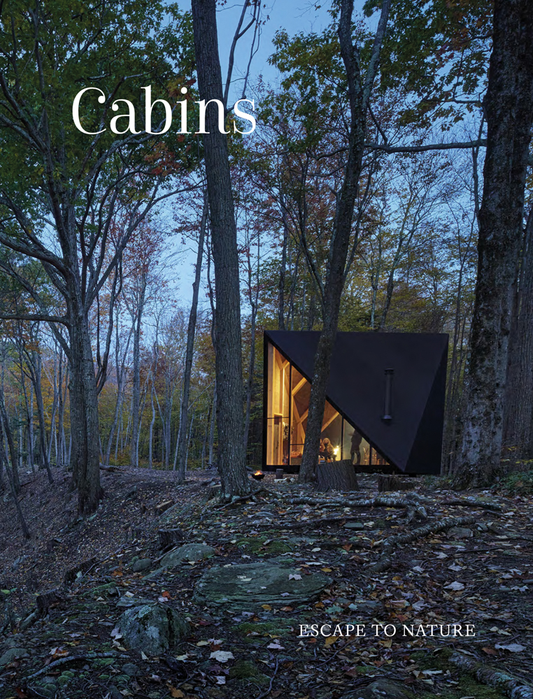 Modern cabin, with interior lights on, in forest at dusk, Cabins in white font to upper left.