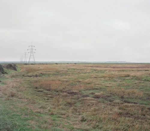 Landscape book cover of Michael Collins Pictures from the Hoo Peninsula, with grassy landscape and pylons in the distance. Published by Verlag Kettler.