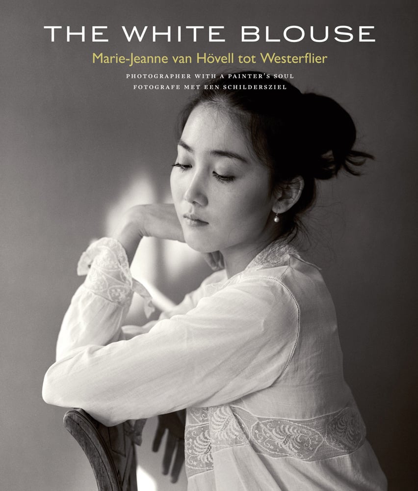 Head and shoulders of Asian female in elegant pose, wearing antique white blouse, THE WHITE BLOUSE in white font above.