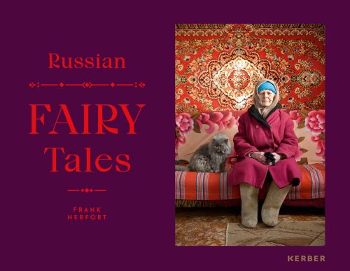Babushka Aleksandra in traditional handmade Russian felt boots, grey cat next to her, on aubergine cover, Russian FAIRY TALES in red font to centre left.