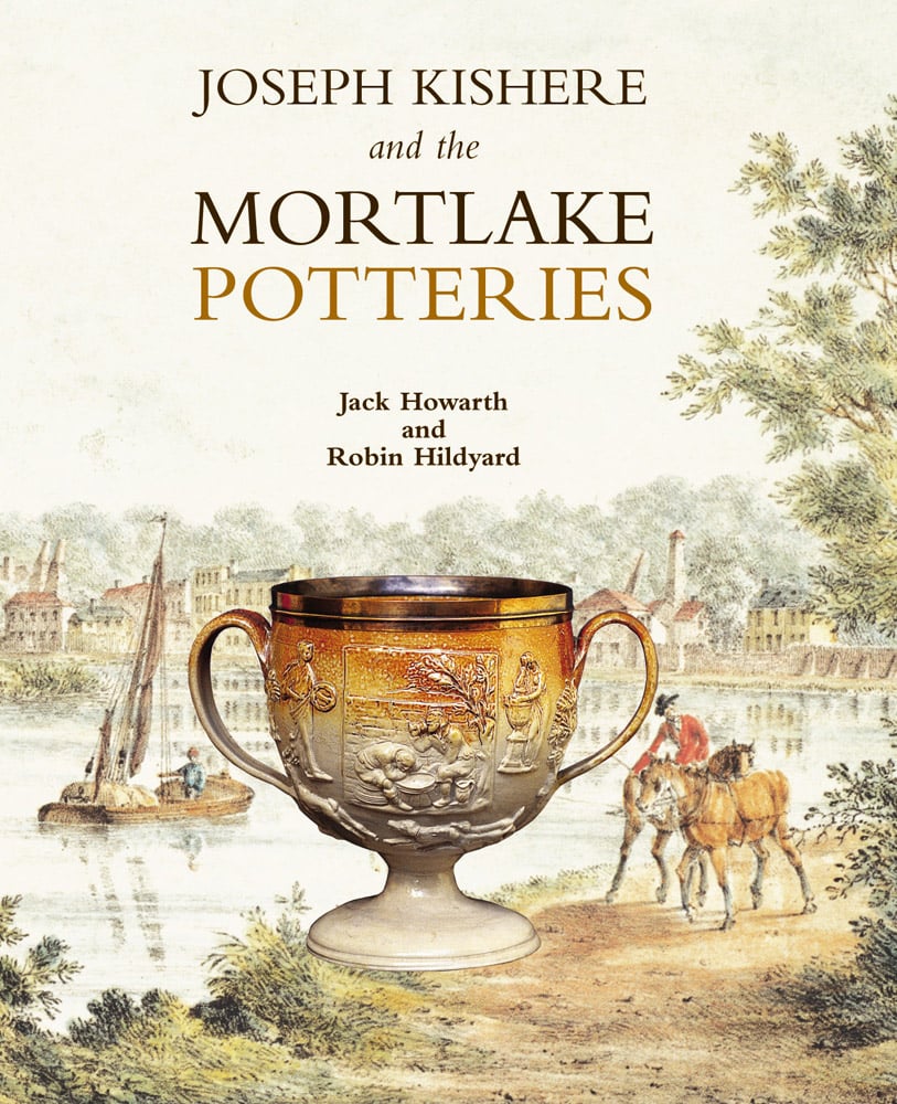 Stoneware cup with handle each side, painting of lake behind, on cover of 'Joseph Kishere and the Mortlake Potteries', by ACC Art Books.