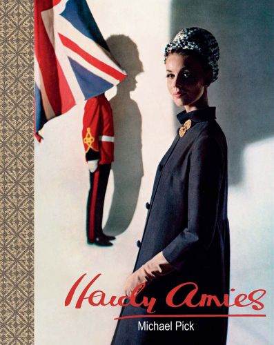 Model in long navy coat, and hat, Union Jack behind, on cover of 'Hardy Amies', by ACC Art Books.