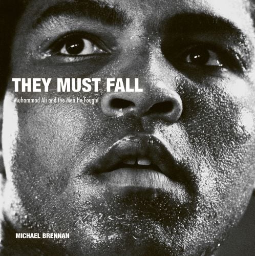 Close up black and white head shot of Muhammad Ali with a sweaty face and They Must Fall Muhammad Ali and the Men He Fought Michael Brennan in white font