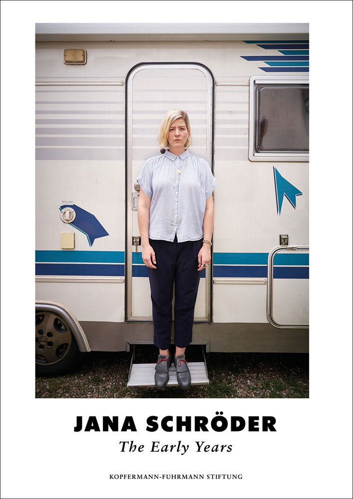 White book cover of Jana Schröder, The Early Years, featuring the female artist staring sternly at the camera as she stand on step of campervan. Published by Verlag Kettler.