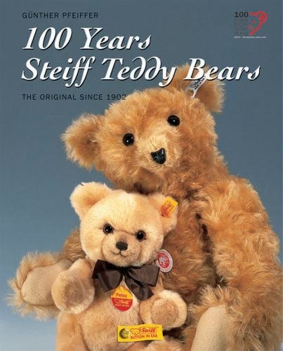 2 light brown Steiff bears, one with brown neck bow, blue grey cover, 100 Years of Steiff Teddy Bears in white font above