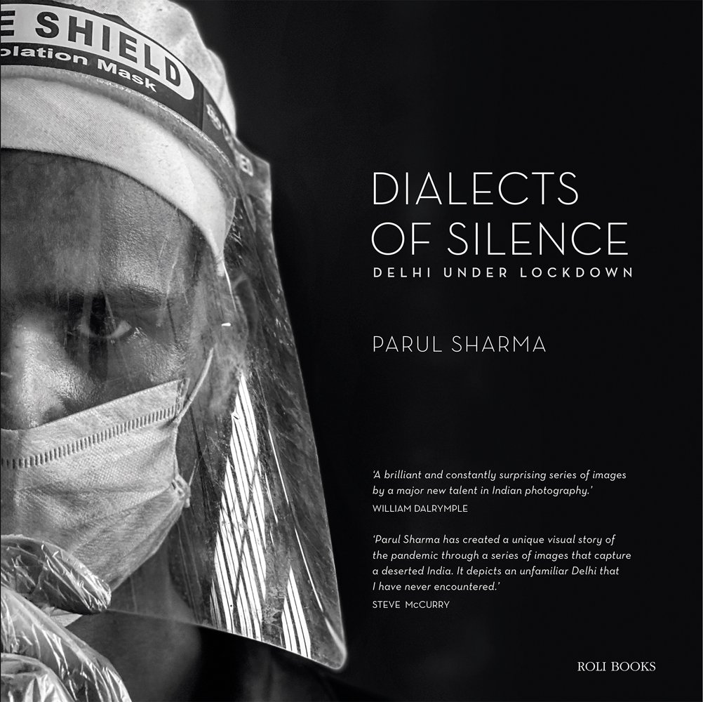 Stark image of medical professional in face shield, surgical mask and gloves, black cover, Dialects of Silence in white font to right.