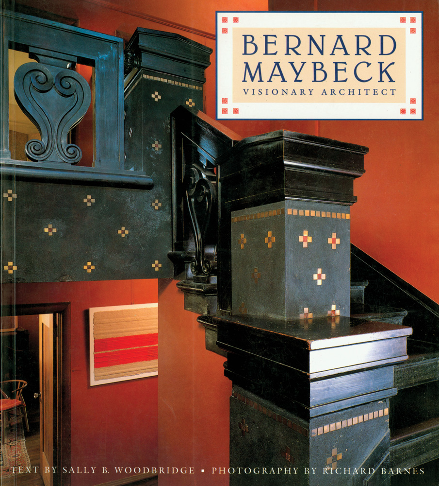 Decorative black wood interior staircase, dark terracotta walls, BERNARD MAYBECK VISIONARY ARCHITECT in in blue font on cream banner to top right.