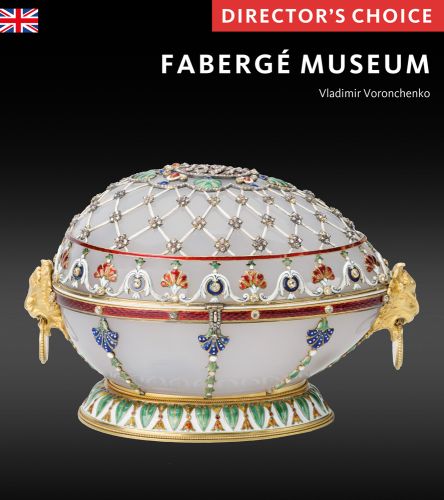 Ornate Faberge egg of off white, gold, green, blue and orange with a latticed top and gold side handles with Faberge Museum in white font above