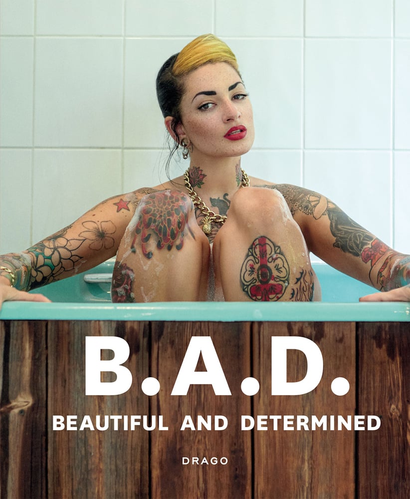 White tattooed model sitting in bathtub, B.A.D. BEAUTIFUL AND DETERMINED, in white font below.