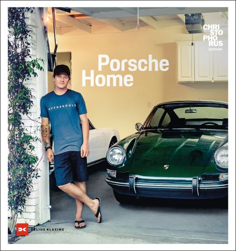 Man in summer clothes and flipflops leaning against brick garage with dark green Porsche inside, Porsche Home in white font above by Delius Klasing.