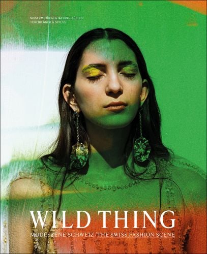 Head and shoulder green filtered shot of model with closed eyes in dress and long earrings and Wild Thing in white font