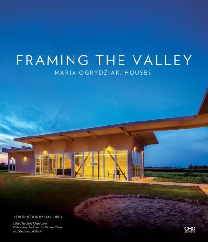 Single flat roof building illuminated by exterior lights under dusk blue sky with Framing The Valley in white font above