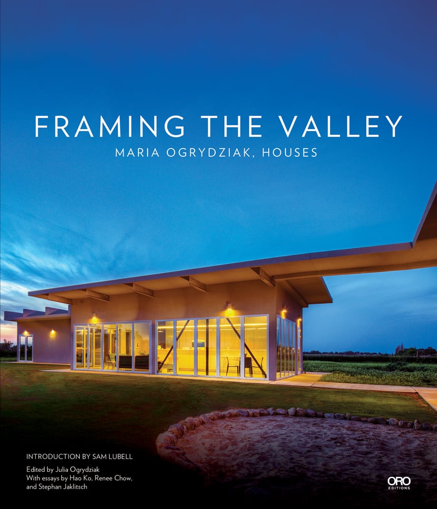 Single flat roof building illuminated by exterior lights under dusk blue sky with Framing The Valley in white font above