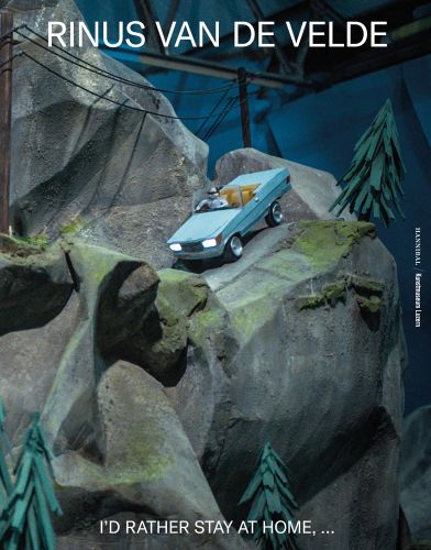Blue roofless car sculpture being driven down grey mountain rocks with pine trees with Rinus Van de Velde in white font above