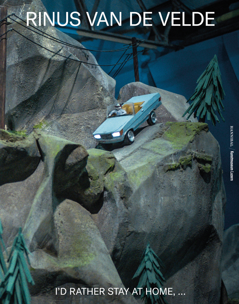 Blue roofless car sculpture being driven down grey mountain rocks with pine trees with Rinus Van de Velde in white font above