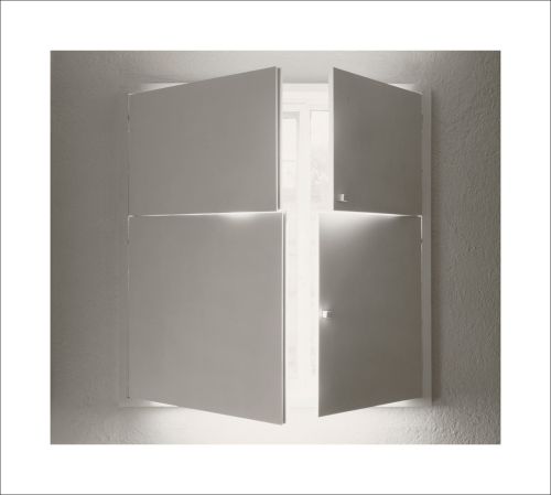 Photo of white wall with small white sculpture of two white split doors opening to reveal an illuminated inside