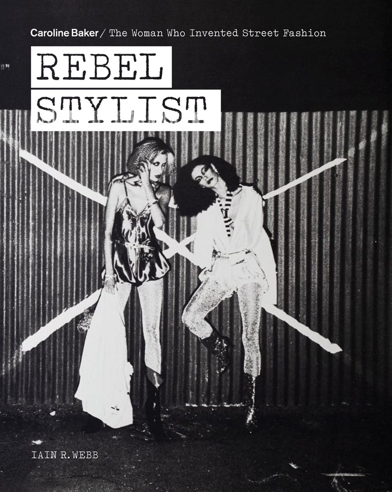 Two fashion models posing in front of corrugated fence with large white X, REBEL STYLIST in white stencil font above.