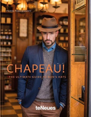 White male model in fedora hat, navy jacket and brown trousers, CHAPEAU! in orange font to lower left of cover.