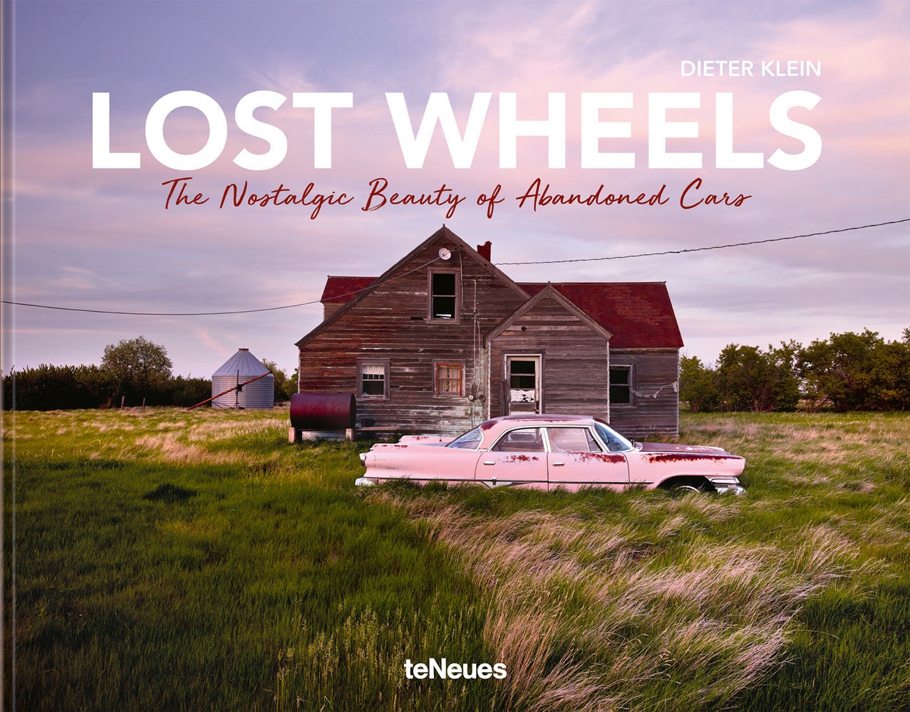 Abandoned pink Cadillac outside wood house in American landscape, LOST WHEELS, in white font above.