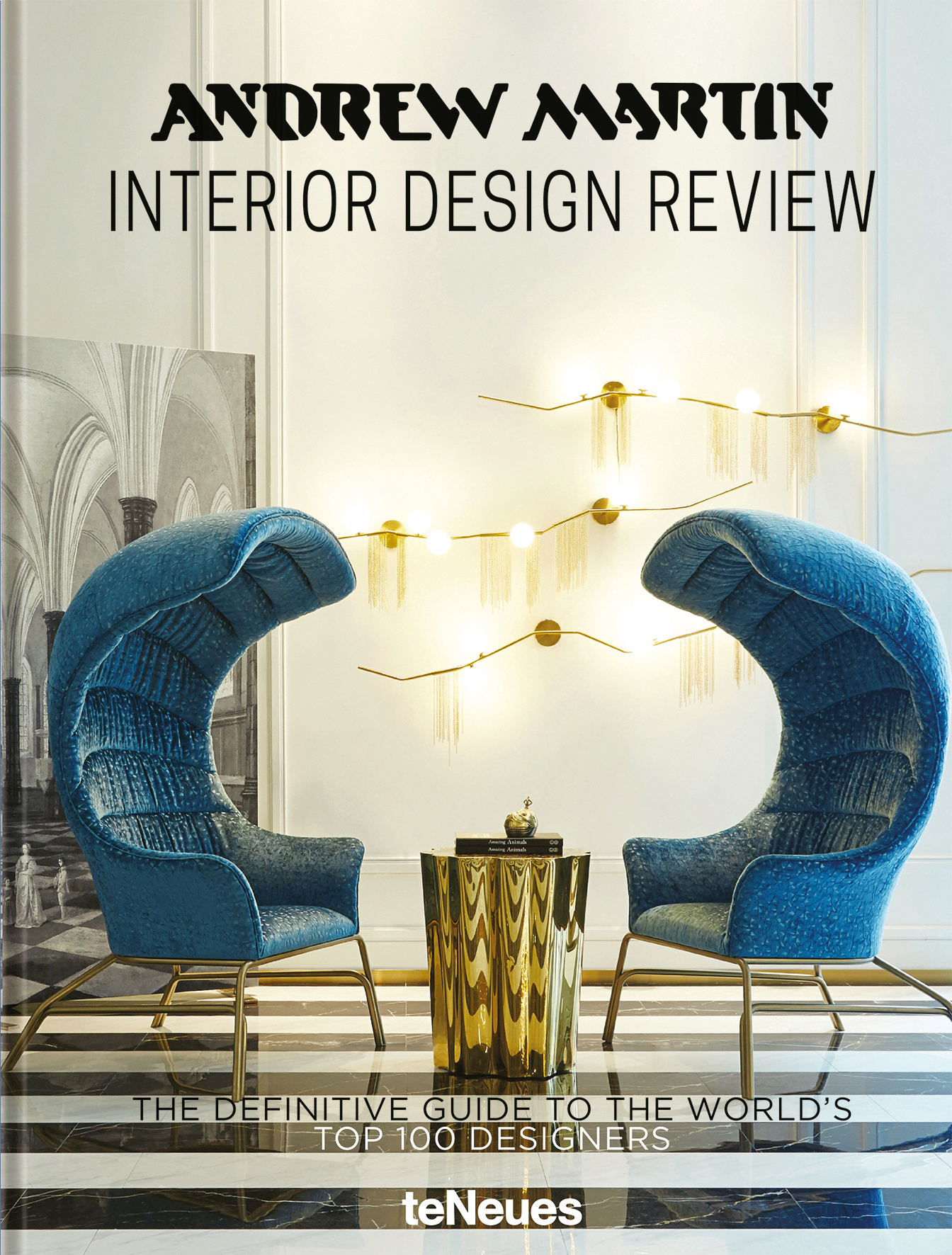 Luxury interior space with two blue velvet curved chairs, gold centre table, ANDREW MARTIN INTERIOR DESIGN REVIEW, in black font above.