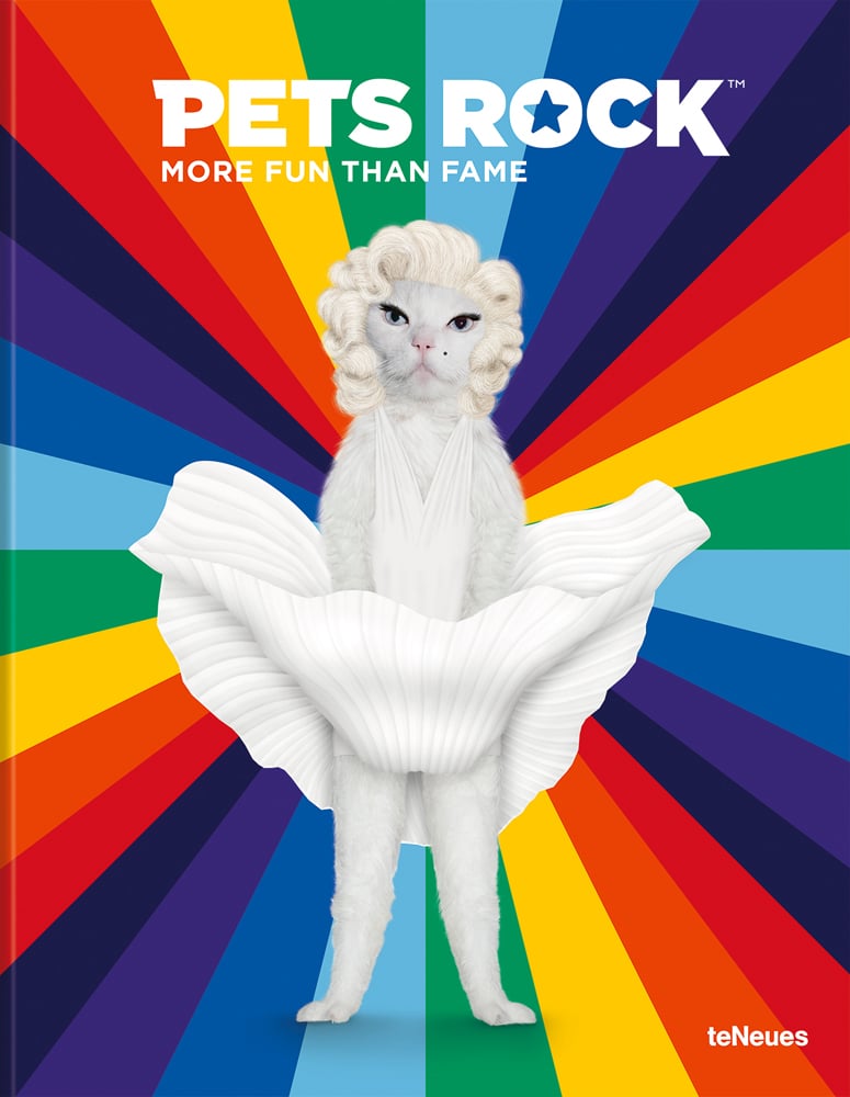 Funny shot of standing white cat dressed as Marilyn Monroe on rainbow patterned cover with Pets Rock More Fun than Fame in white font above