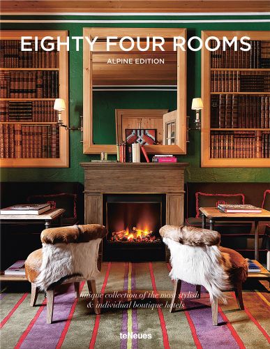 Ski resort interior with roaring fire, two fur chairs in front, 'EIGHTY FOUR ROOMS', in white font above, by teNeues Books.