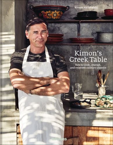 Kimon Riefenstahl in white apron, standing in kitchen, 'Kimon’s Greek Table', in white font to centre right of cover, by teNeues Books.