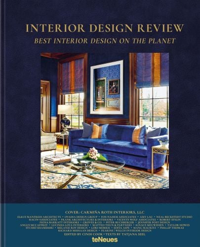 Lavish interior room with electric blue sofa, blue and gold blinds, on navy cover, INTERIOR DESIGN REVIEW, in gold font above.