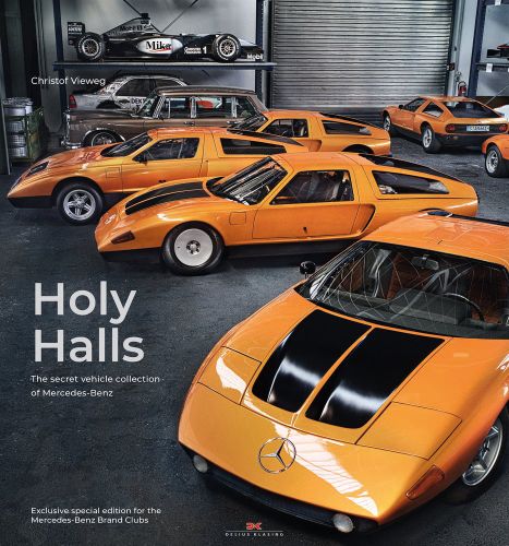 Warehouse interior with 6 bright orange Mercedes models and black F1 car on shelf with Holy Halls in white font