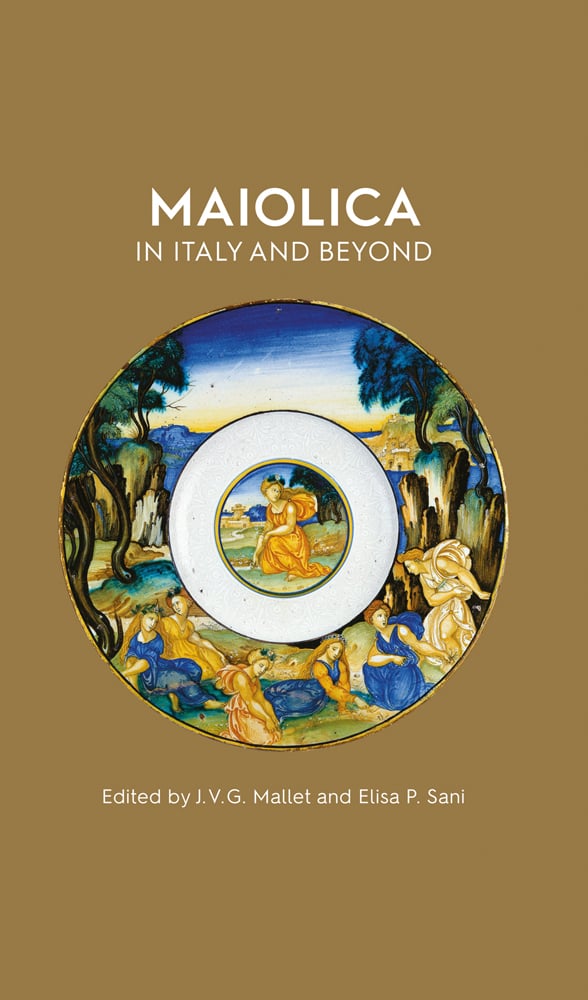 Maiolica dish with gold edge and landscape painting with blue sky on gold brown cover with Maiolica in Italy and Beyond in white font above