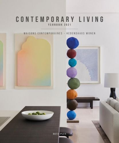 Interior with ball sculpture, long brown table and pastel wall hangings with Contemporary Living Yearbook 2021 in grey font above