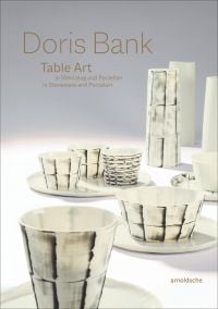 Collection of cream and black cups, saucers and vases, on white and grey cover, of 'Doris Bank, Table Art in Stoneware and Porcelain', by Arnoldsche Art Publishers.
