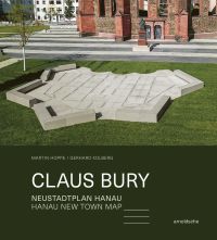 Colour photo of geometric concrete shape on green grass in townscape with Claus Bury in white font on dark green border below