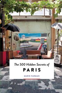 Exterior space arched with leaf vines over 3 seats 2 umbrellas on long poles and backdrop sheet with airliner on with The 500 Hidden Secrets of Paris in a white box below in black font