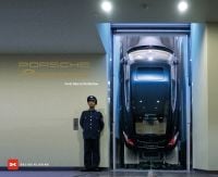 Porsche Panamera parked on vertical ramp, man in blue uniform on guard to left, on cover of 'Porsche Panamera, From Idea to Perfection', by Delius Klasing.
