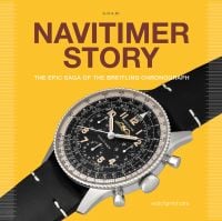 Black and silver Navitimer watch, on yellow cover, NAVITIMER STORY in brown font above