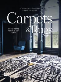 Living interior with navy wall panelling, large black and white rug, arch windows, on cover of 'Carpets & Rugs, Every home needs a soft spot', by Lannoo Publishers.