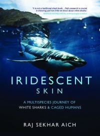 Book cover of Iridescent Skin: A Multispecies Journey of White Sharks & Caged Humans, with a shark swimming below the surface of ocean. Published by Niyogi Books.