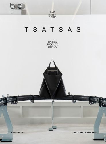 Large black leather bag on metal conveyer belt, on white cover, 'TSATSAS, past present future', by Arnoldsche Art Publishers.