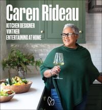 Book cover of Caren Rideau: Kitchen Designer, Vintner, Entertaining at Home, with the designer standing in a kitchen, holding a glass of white wine. Published by Pointed Leaf Press.