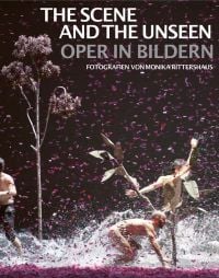 Opera theatre production, three windswept figures with water splashing at feet, tree to left, pink confetti in air, THE SCENE AND THE UNSEEN in white font above.