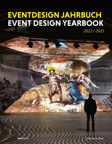 Exhibition space, man looking at figure with wings fighting figure with sword, on mound, EVENT DESIGN YEARBOOK 2022/2023 in white, and yellow font above.