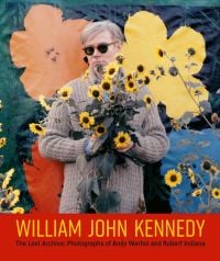 Pop artist Andy Warhol grasping bunch of yellow sunflowers, flower backdrop, WILLIAM JOHN KENNEDY in yellow font on bottom red banner.