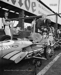 White male racing driver from the sixties, sitting in jacked up with no wheels, on cover of 'CAR RACING 1969' by Editions Cercle d'Art.